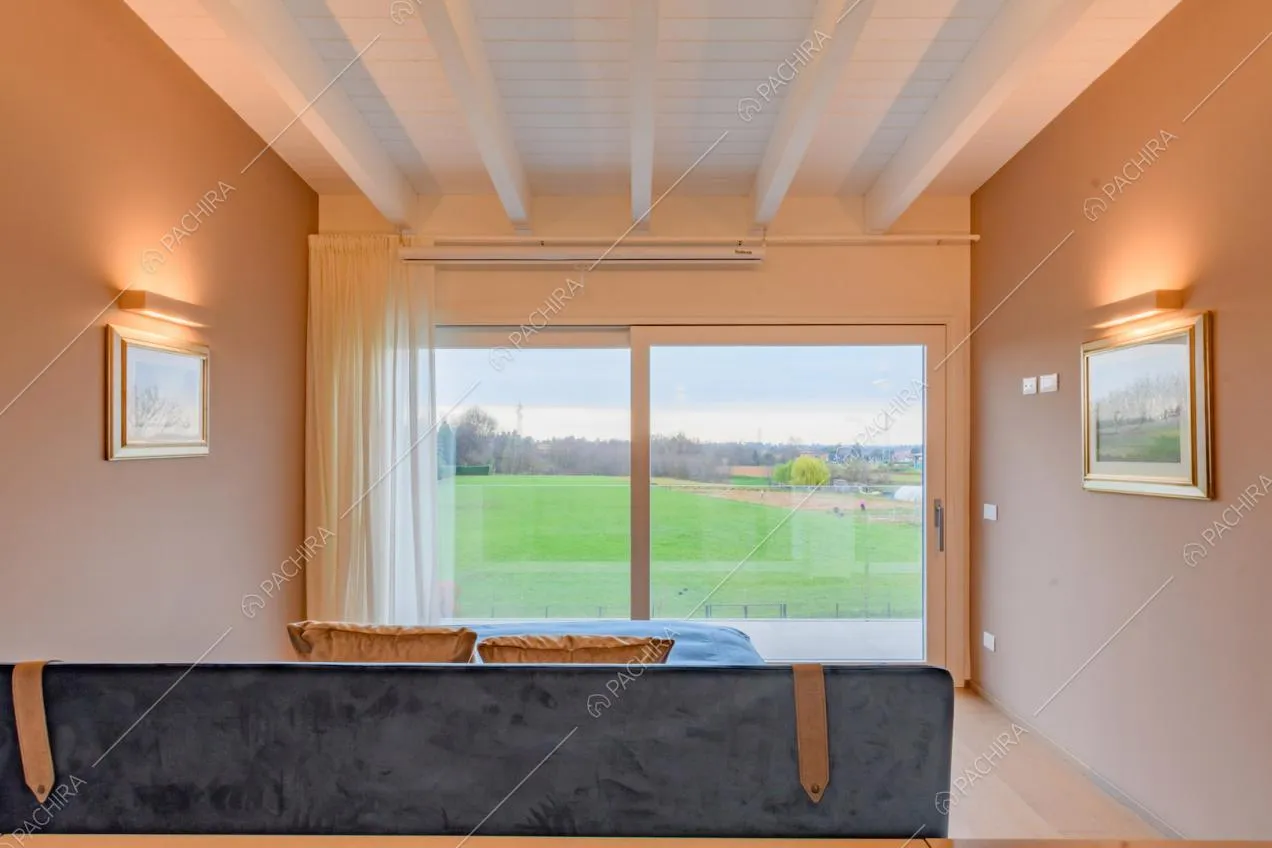 Camera da letto matrimoniale con porta-finestra scorrevole e travi a vista sul soffitto