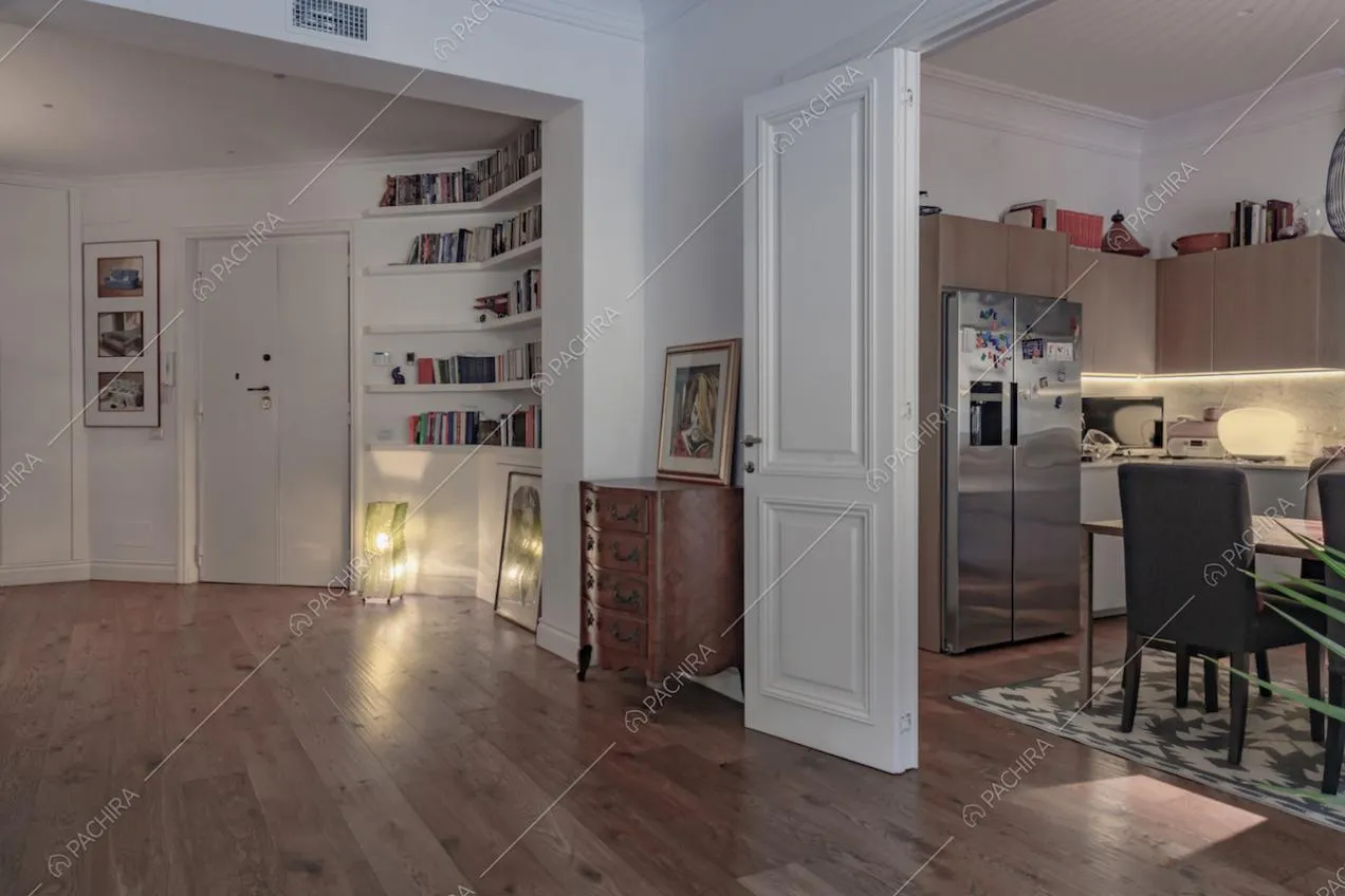 Dal salotto vista sull'ingresso e sulla cucina separata da porte bianche con boiserie
