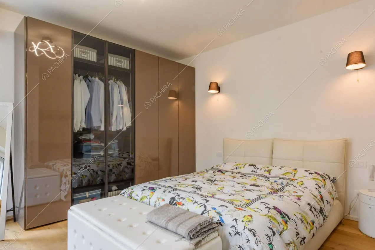 Luminosa camera da letto matrimoniale con pareti bianche e pavimento in parquet