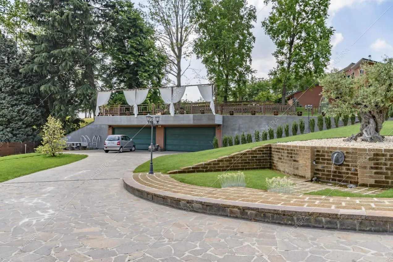 Vista sui garage della villa e vialetto di accesso in lastre di pietra nel curatissimo giardino
