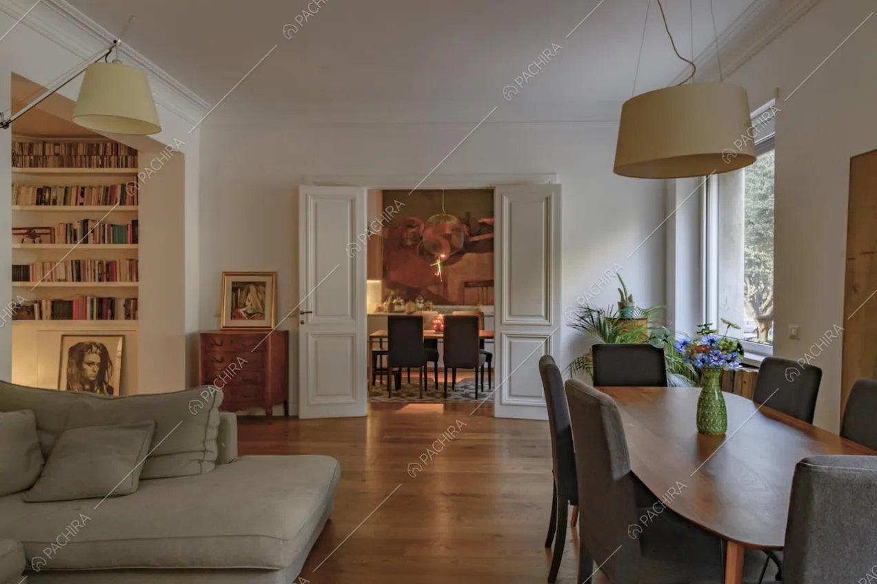 Sala con tavolo da pranzo in legno, divano grigio e vista sulla cucina con tavolo