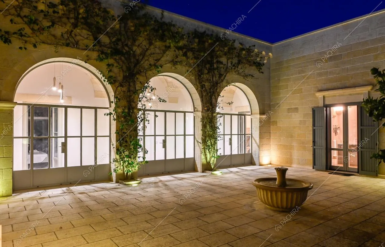 Porte-finestre in stile industriale, facciata con rampicanti e fontana nel cortile della villa
