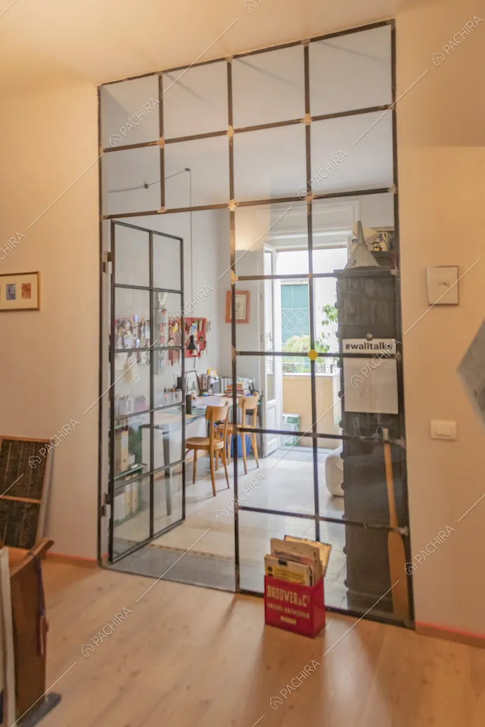 Studio luminoso con vetrata industriale e portariviste da terra