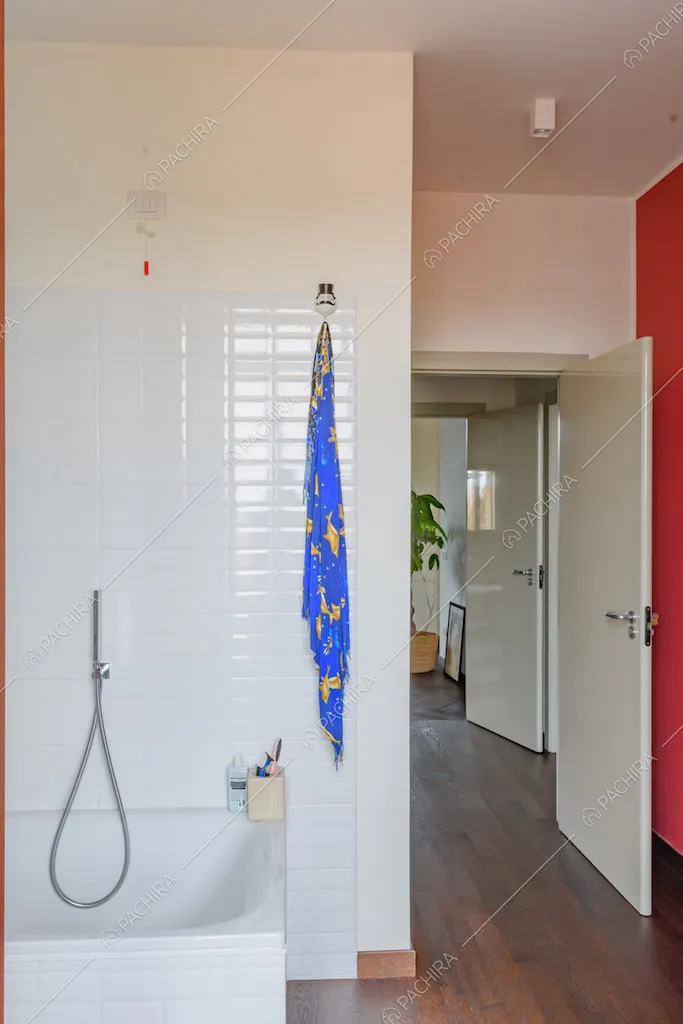 Bagno con vasca, pavimento in parquet parete bianca e parete rossa