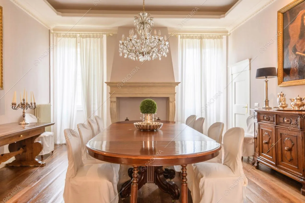 Tavolo da pranzo in legno nella sala co pavimento in parquet, camino e lampadario in cristallo