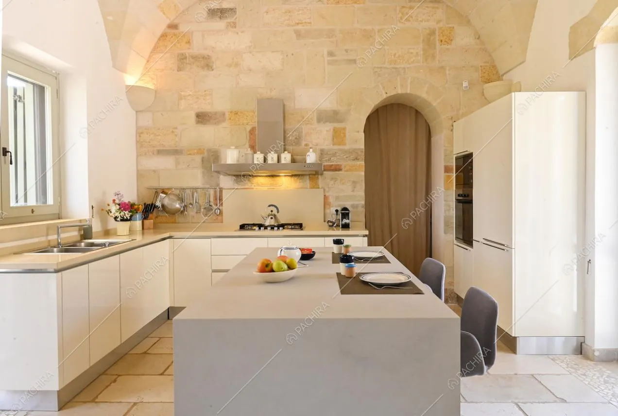 Luminosa cucina con fornelli a gas, isola con bancone e sgabelli e soffitto ad arco