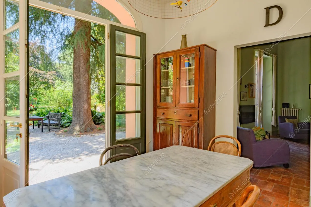 Piano in marmo del tavolo da pranzo e vista sul salotto con pareti verde e poltrone viola