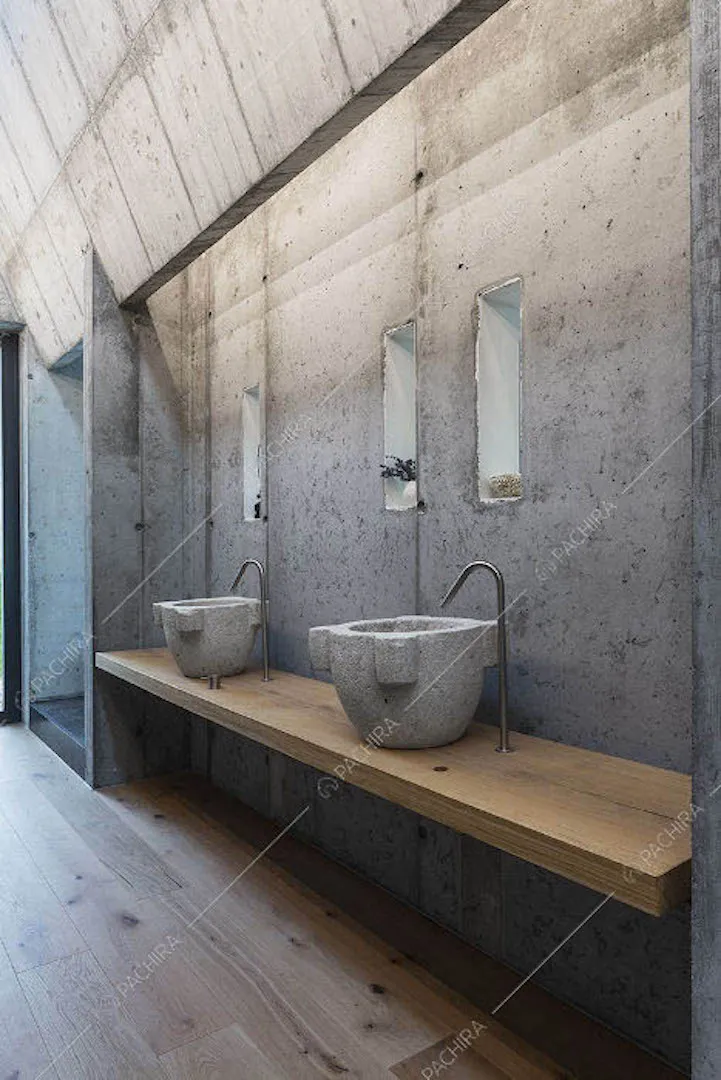 Bagno con pavimento in parquet, pareti in cemento e doppio lavandino