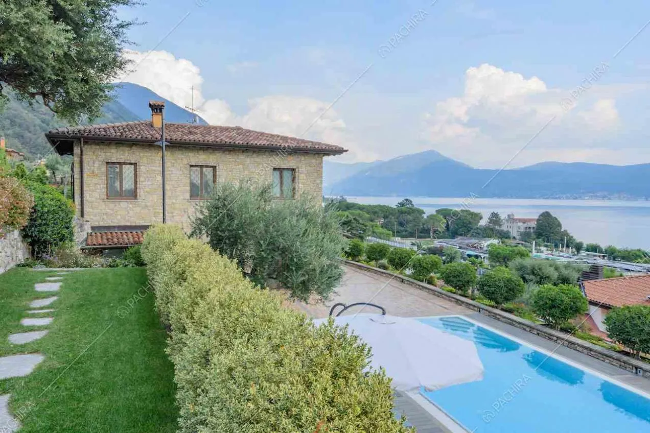 Vialetto in lastre di pietra, siepe e piscina sulla terrazza con vista sul lago