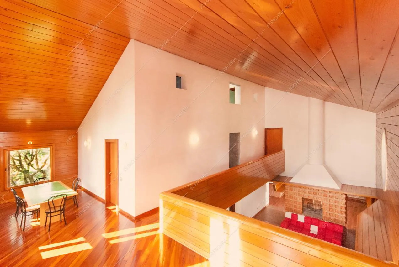 Soffitto rivestito in legno e vista sulla zona giorno con camino