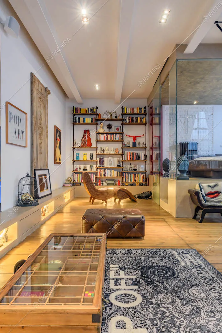 Pavimento in parquet nel salotto con pareti bianche, travi a vista e libreria