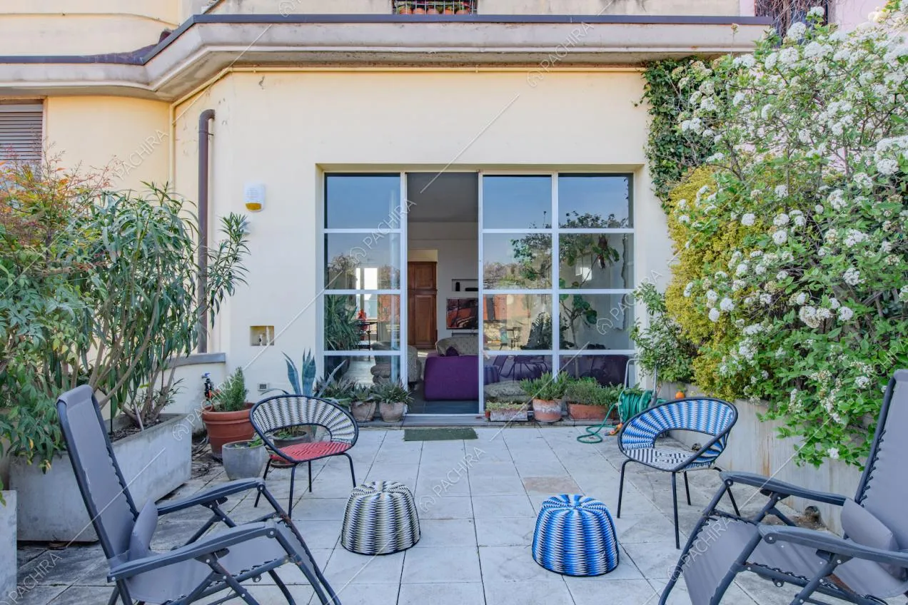 Terrazza con fioriere, sdraio e porta-finestra in stile industriale