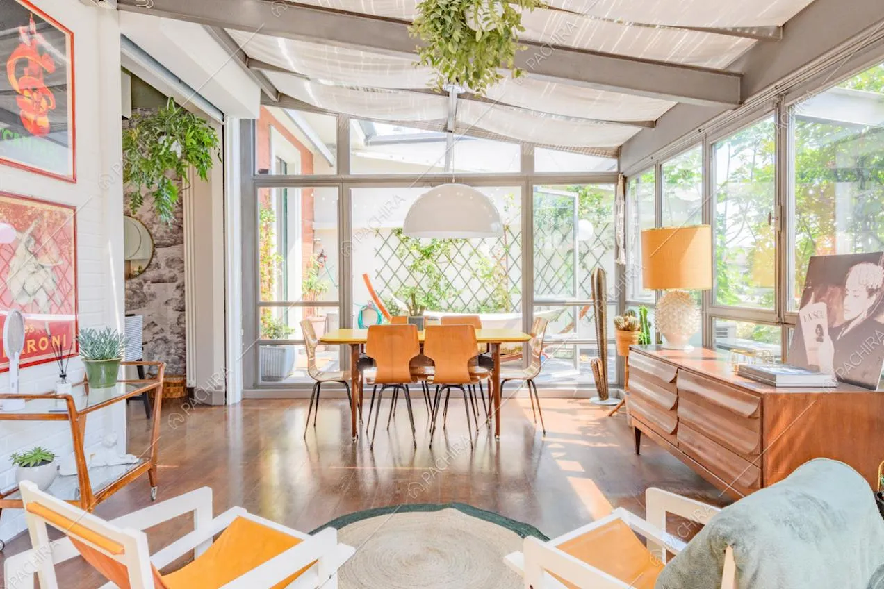 Luminosa veranda con tavolo da pranzo giallo, lampadario e pavimento in parquet