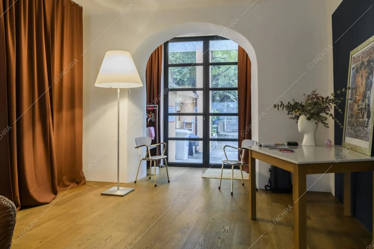Studio con pavimento in parquet, pareti bianche e arco che apre la visuale sul giardino