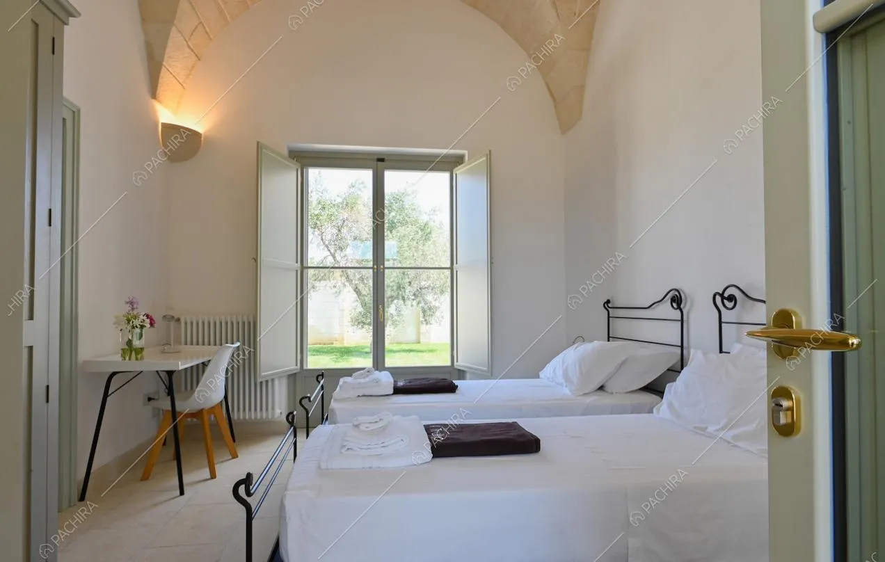 Camera da letto doppia con scrivania, pareti bianche e soffitto ad arco