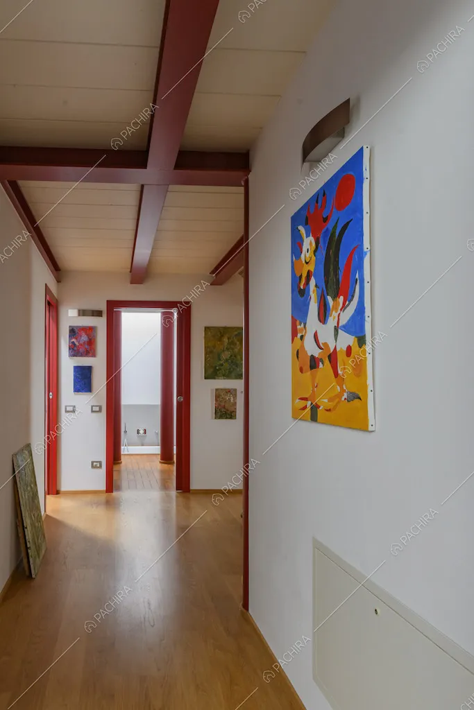 Corridoio con pavimento in parquet, pareti bianche e infissi rossi