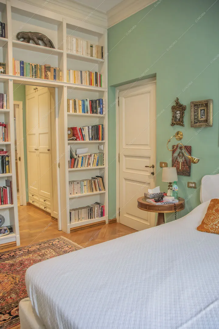 Letto matrimoniale nella camera dalle pareti verdi e con porte bianche con boiserie