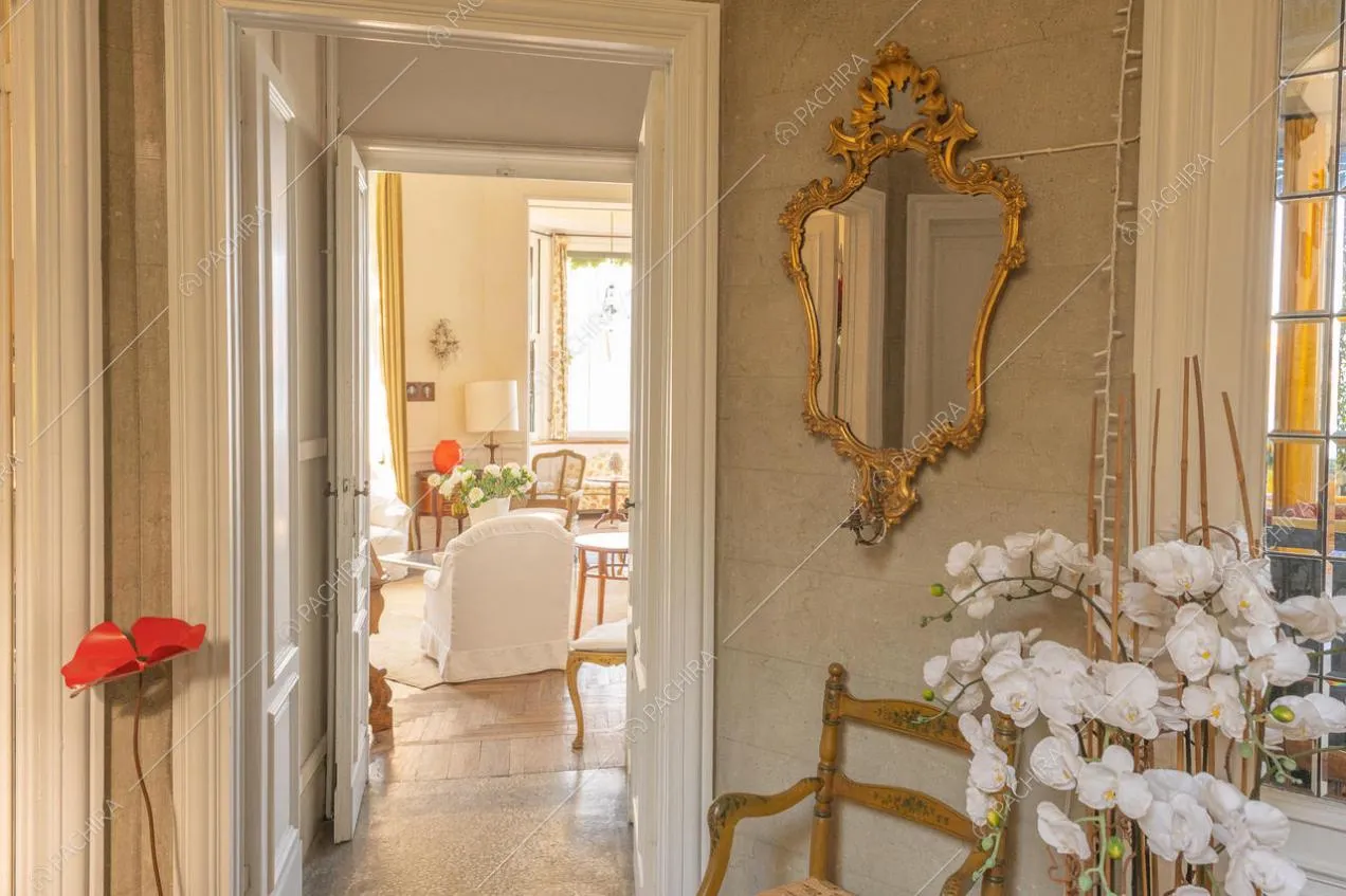 Visuale su zona living, con arredi in tonalità chiare e specchio d'epoca