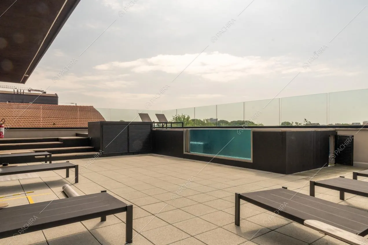 Piscina con vista sullo skyline sulla terrazza con lettini neri e pavimento in piastrelle bianche