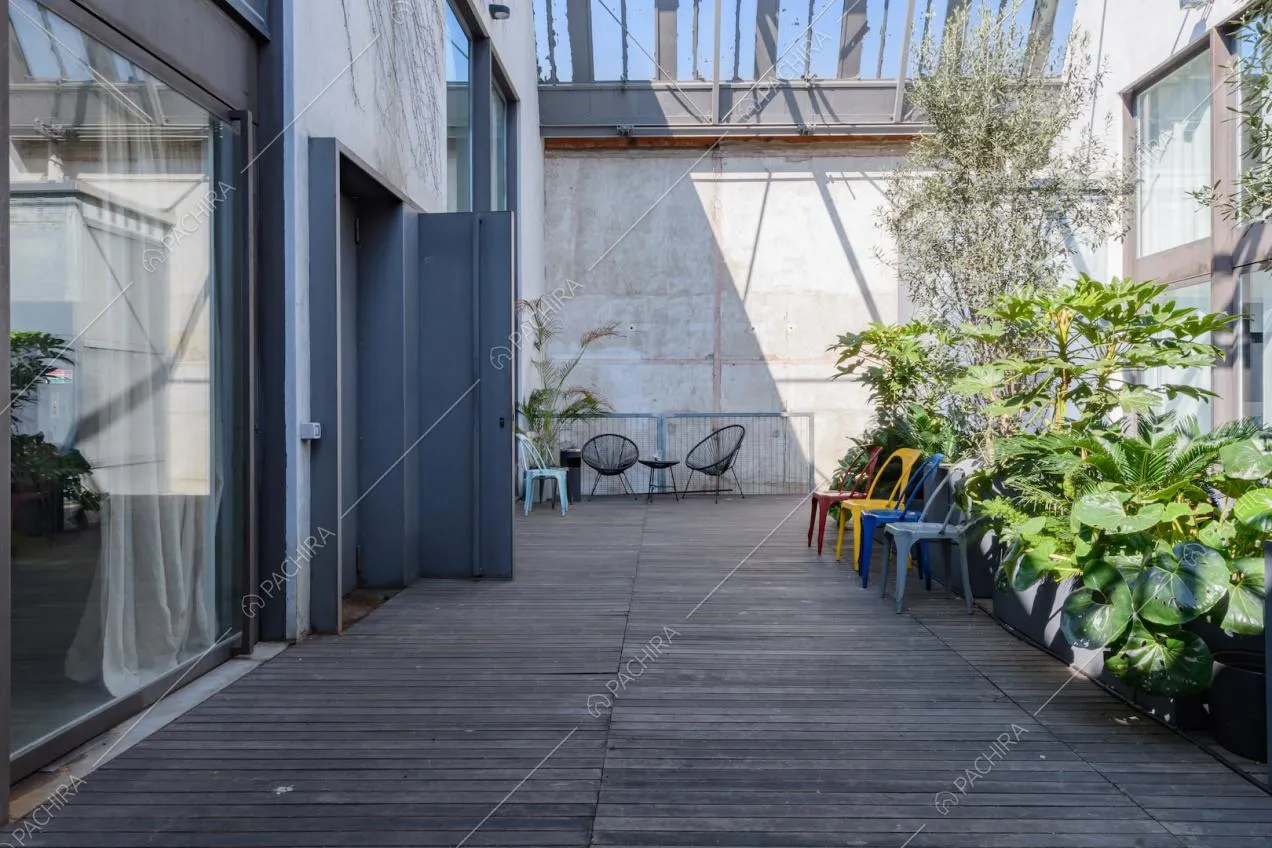 Grande terrazza con struttura ex industriale e pavimento in parquet da esterni