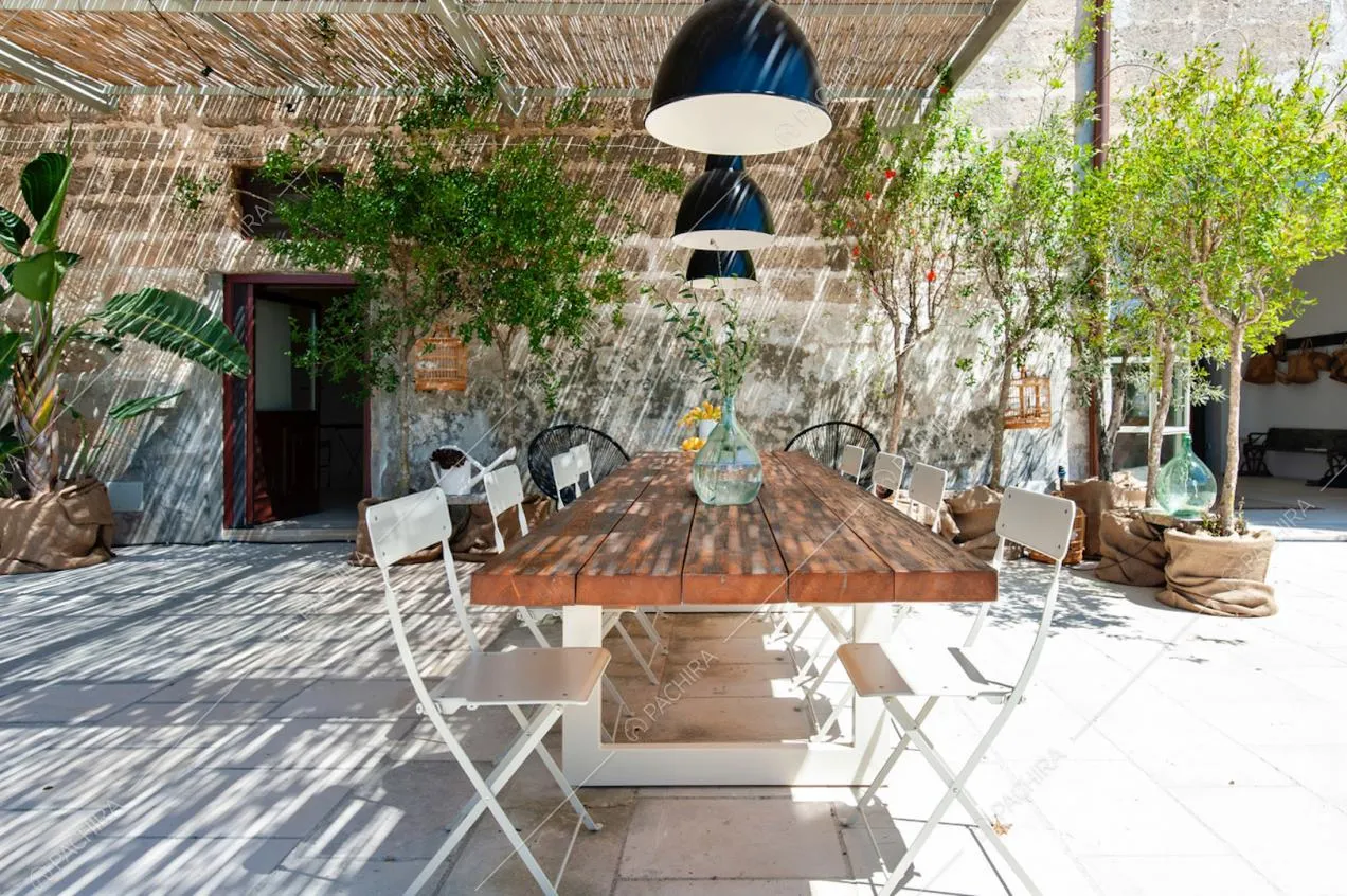 Zona pranzo esterna con tettoia in bambù, lampade e piante in vaso
