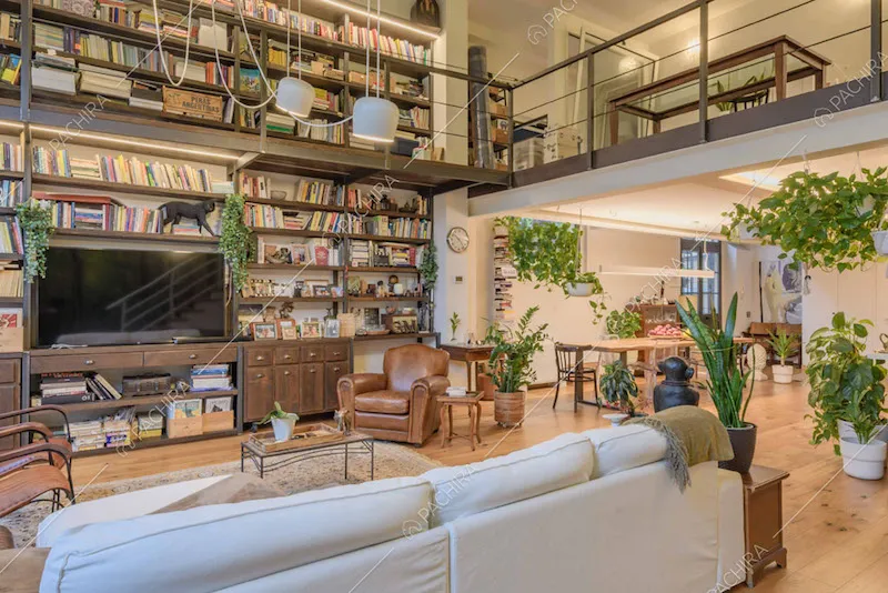 Luminosa zona living con divano bianco, libreria a parete e pavimento in parquet
