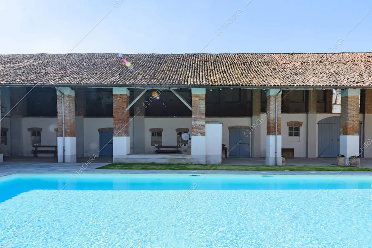 Piscina con vista sul portico con colonne in mattoni a vista dell'ex fienile
