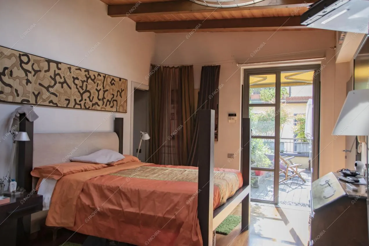 Luminosa camera da letto matrimoniale con porte-finestre per accedere alla terrazza e pareti bianche