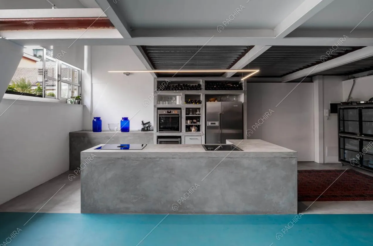 Cucina grigia a isola con fornelli a gas nel luminoso open space con pavimento in resina
