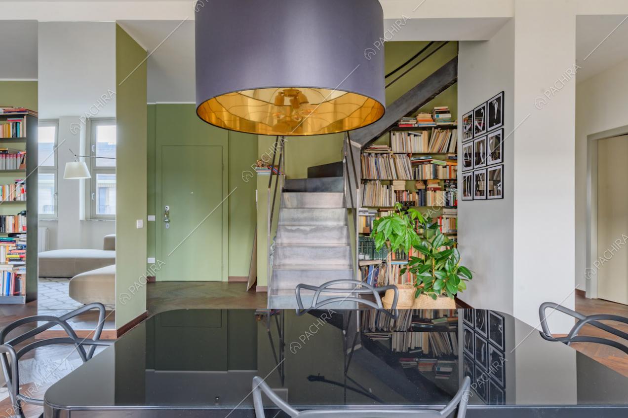 Tavolo da pranzo nero nella luminosa zona living con scale e libreria