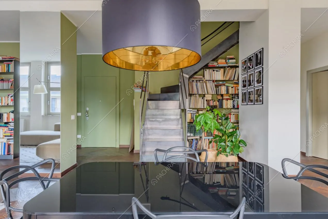 Tavolo da pranzo nero nella luminosa zona living con scale e libreria