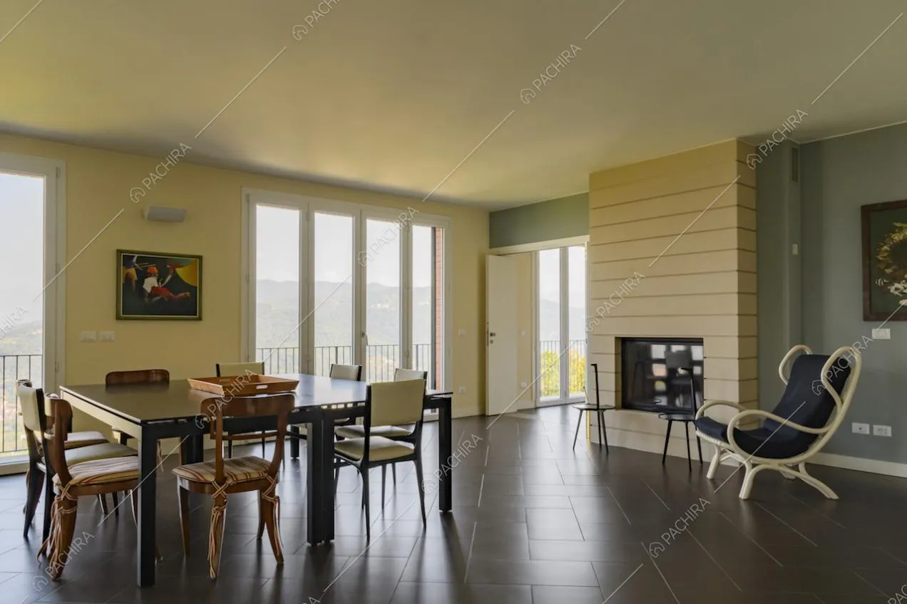 Sala da pranzo con camino, collegata a un'altra sala e con ampie vetrate