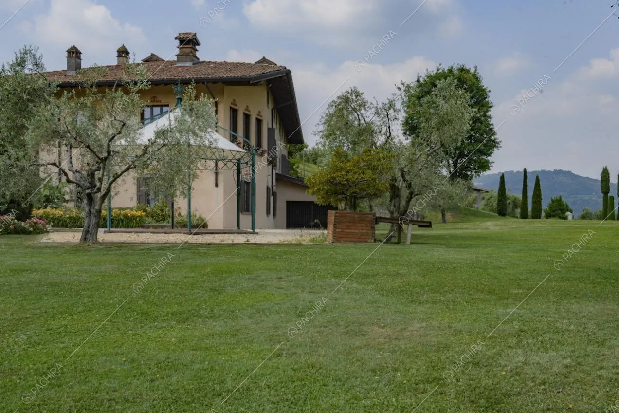 Dettaglio esterno della villa con alberi e prato