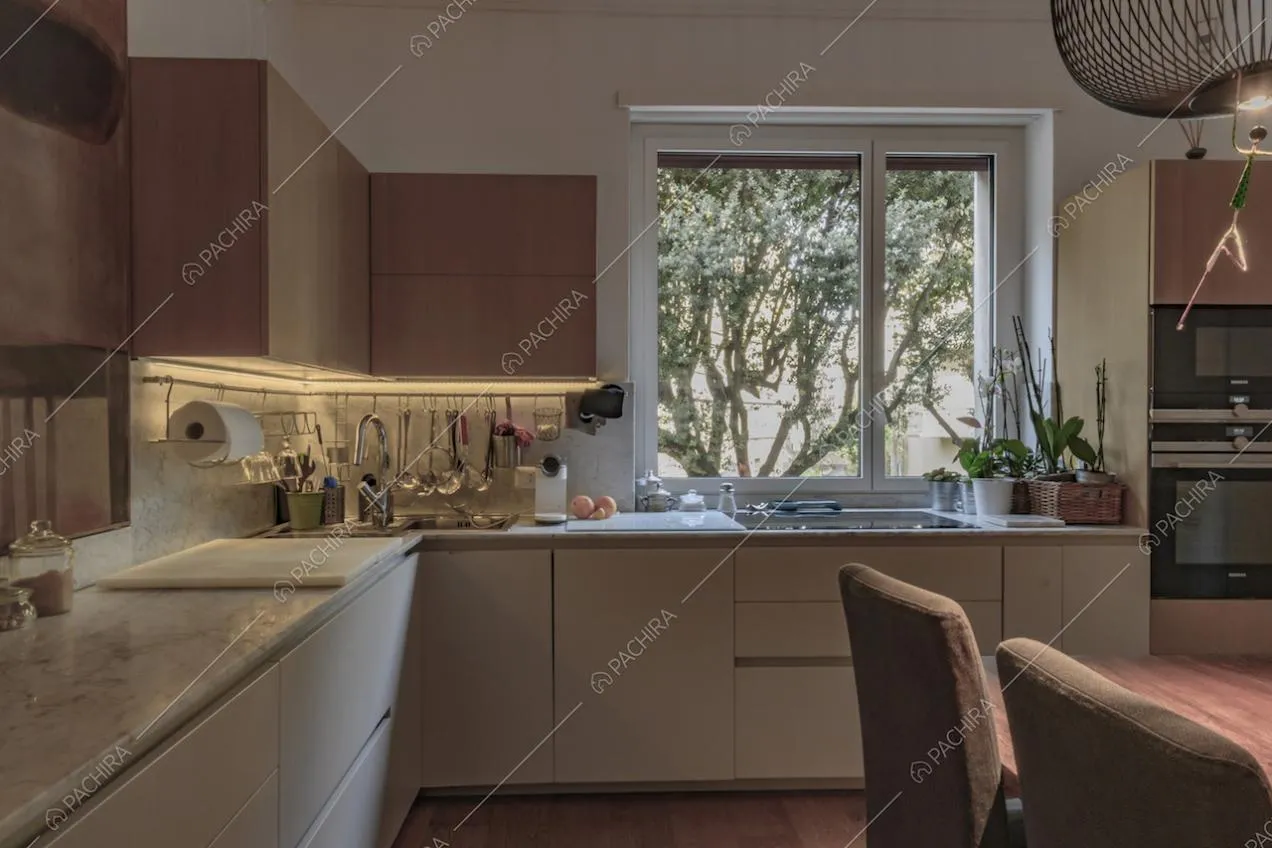 Cucina con piano di lavoro e paraschizzi in marmo, vetrate e tavolo da pranzo in legno