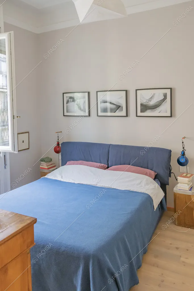 Letto matrimoniale, comodini in legno e quadri sulla parete