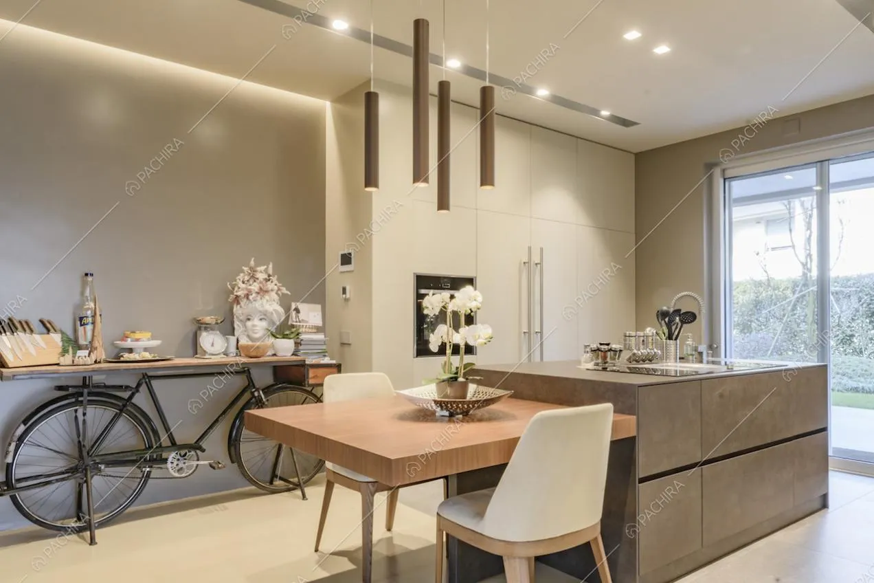 Cucina con tavolo da pranzo in legno unito all'isola e porta-finestra scorrevole