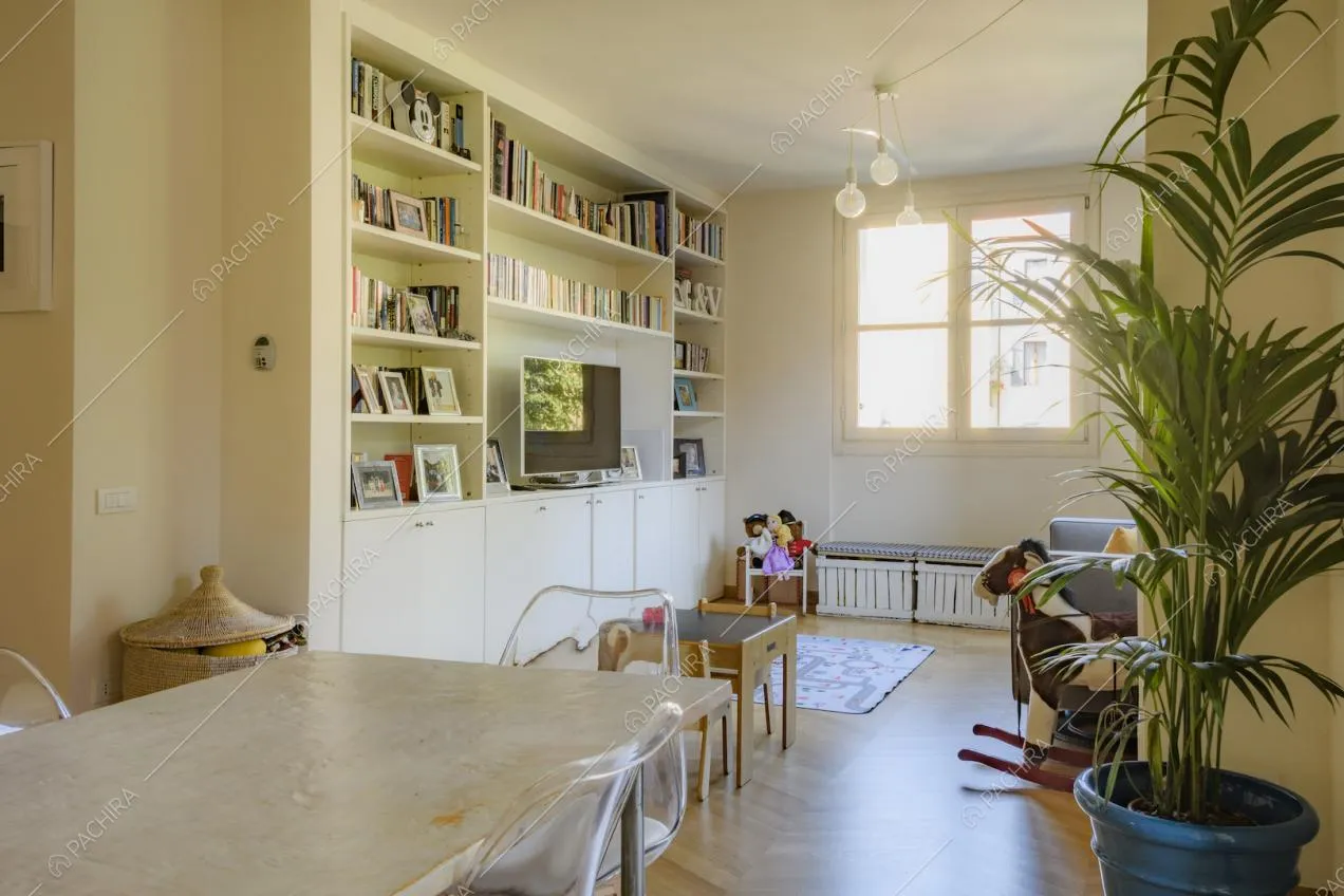 Libreria contenente libri e portafoto di fianco alla finestra quadrata