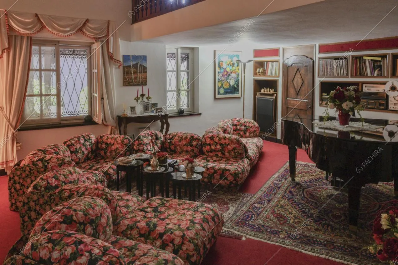 Salotto sui toni del rosso con poltroncine colorate e pianoforte