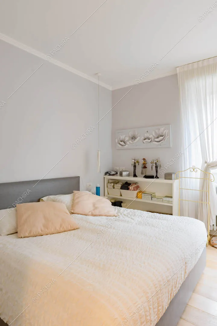 Luminosa camera da letto matrimoniale con pareti grigie e pavimento in parquet
