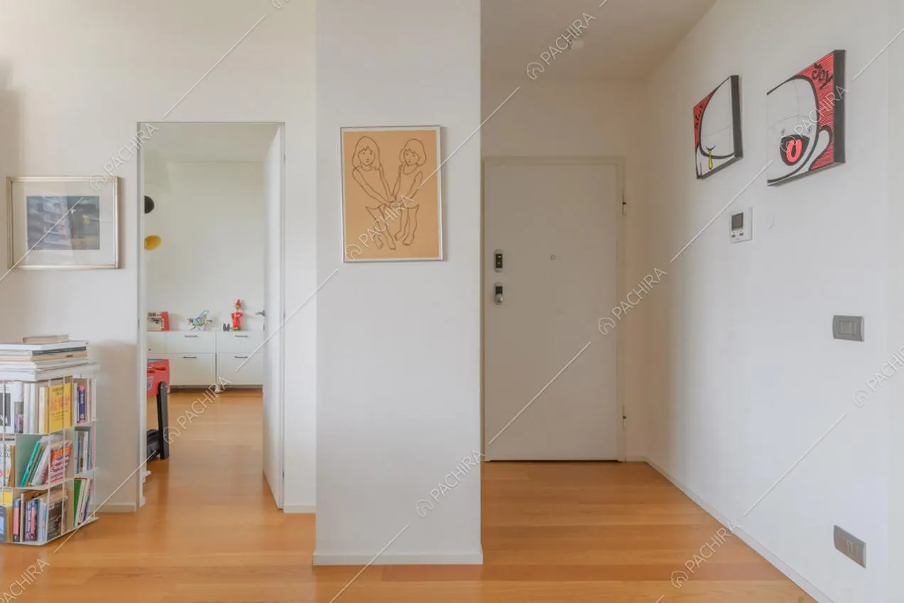 Pavimento in parquet, pareti bianche e scorcio sulla cucina dall'ingresso