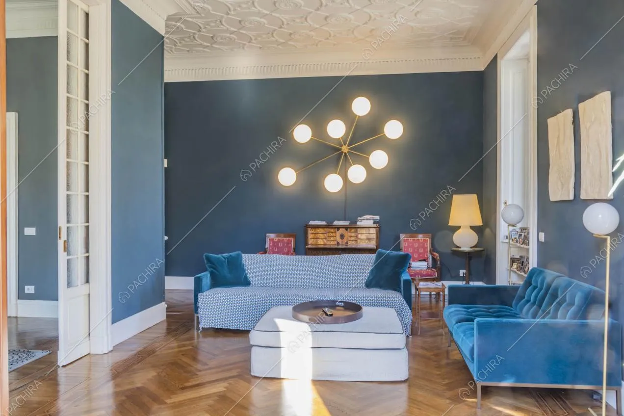 Salotto con pareti blu, pavimento in parquet a spina di pesce e boiserie sul soffitto