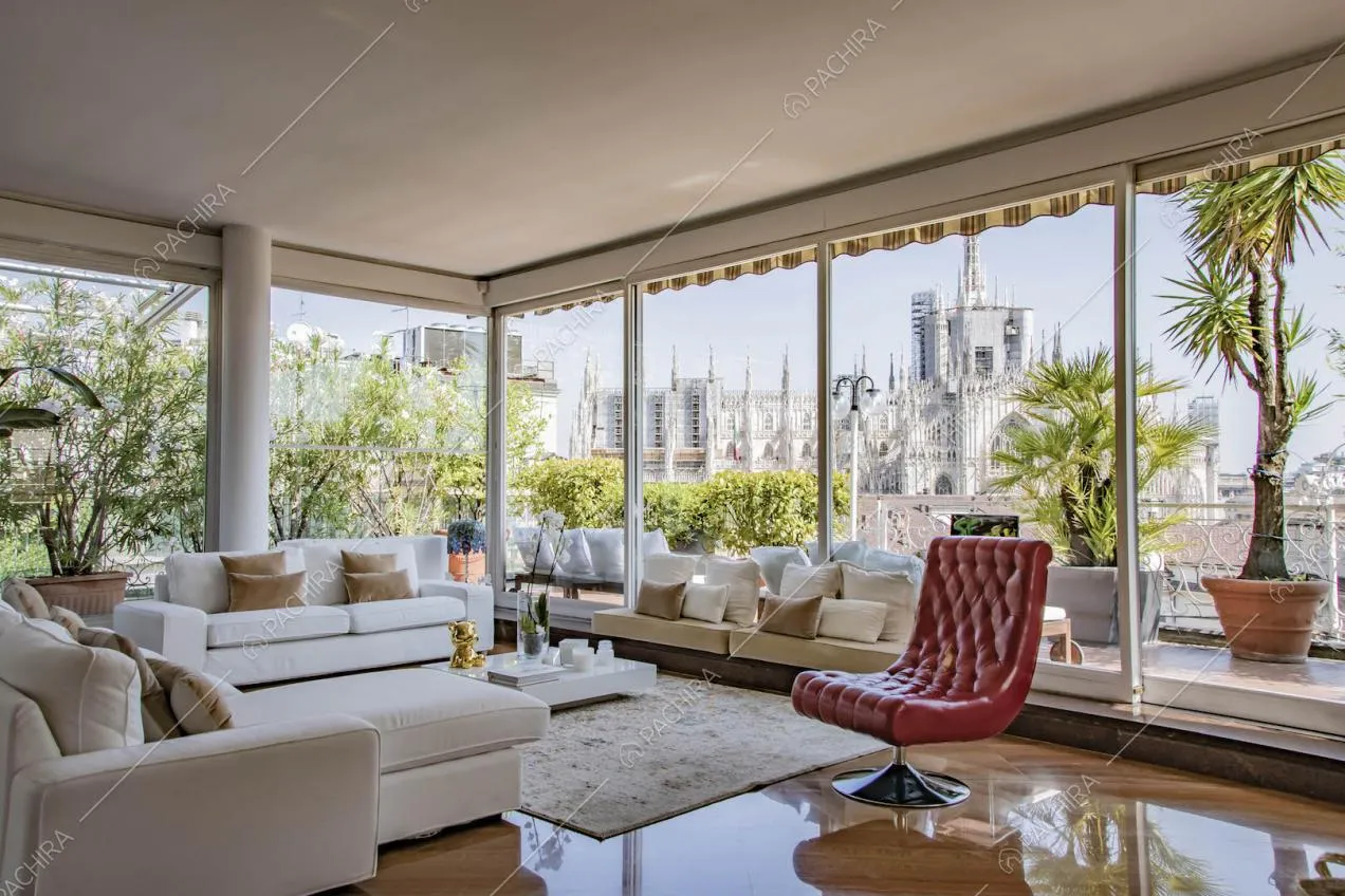 Divani bianchi nella luminosa zona living con grandi vetrate e pavimento in parquet