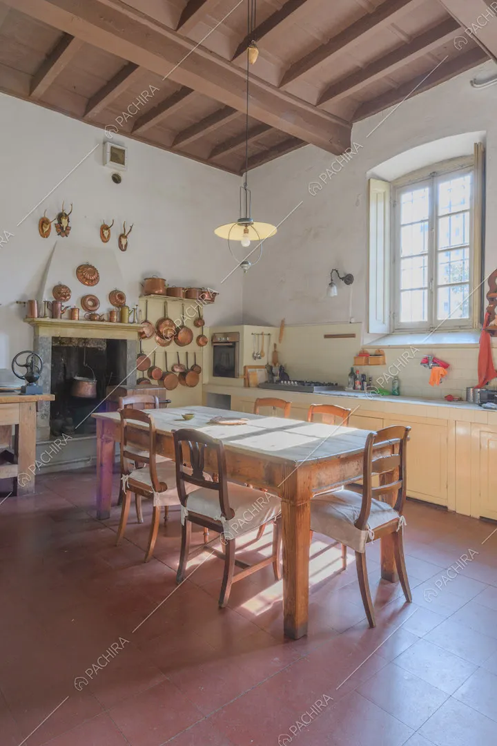 Cucina a parete con camino, tavolo da pranzo in legno e soffitto in travi in legno