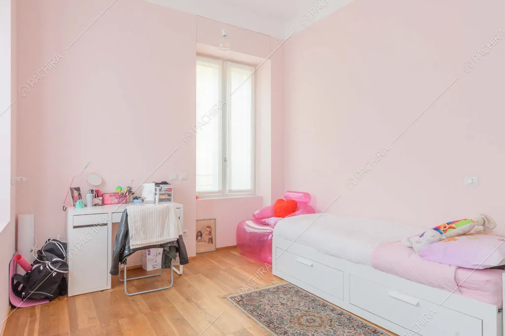 Camera da letto dei bambini con pareti rosa, scrivania e pavimento in parquet