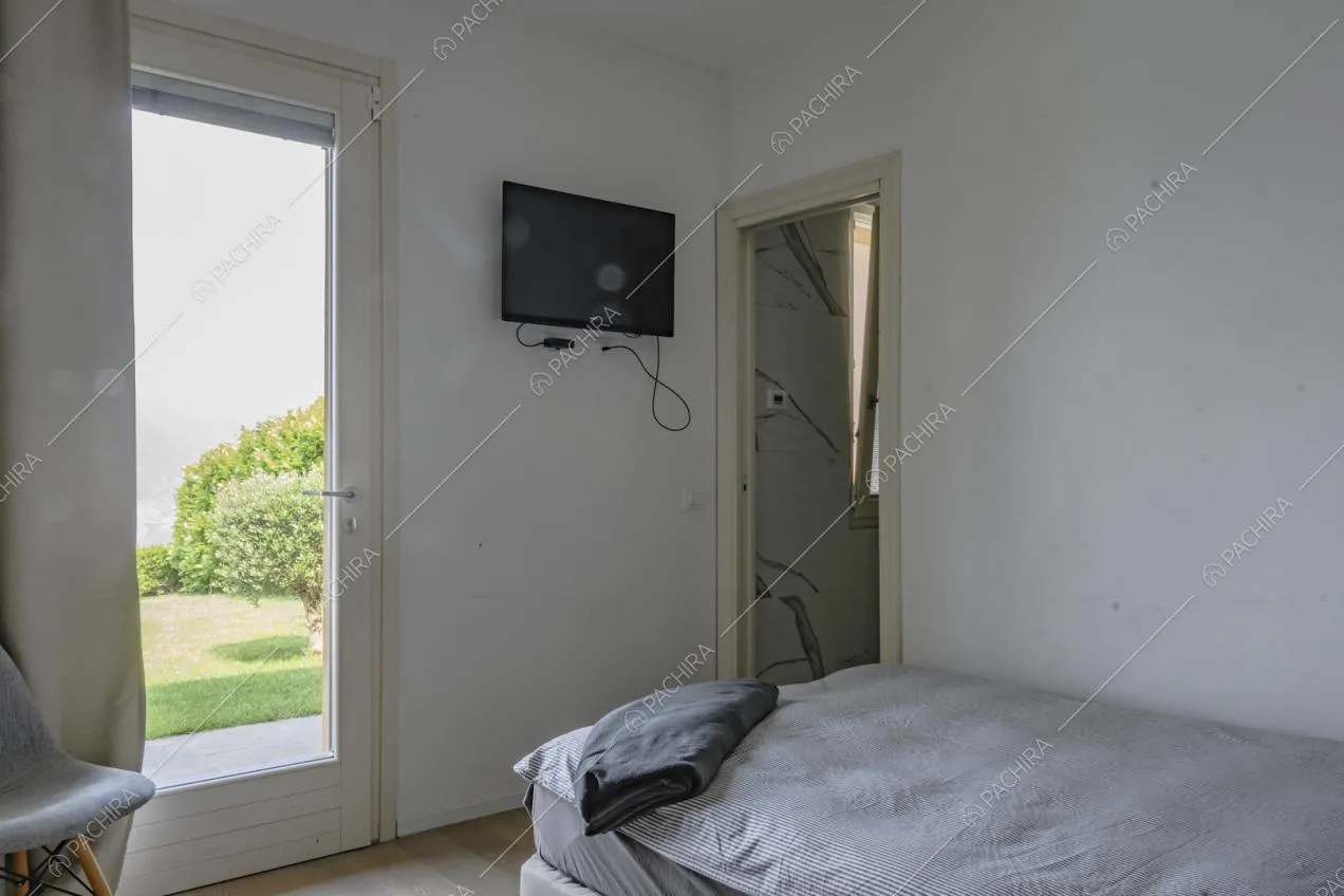 Letto singolo e piccolo televisore appeso alla parete