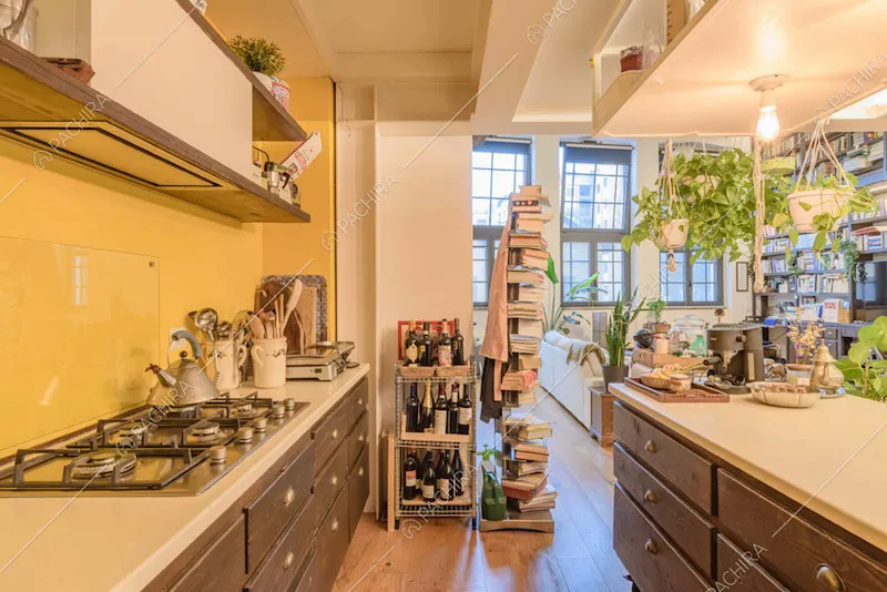Parete gialla della cucina con fornelli a gas, isola e pavimento in parquet