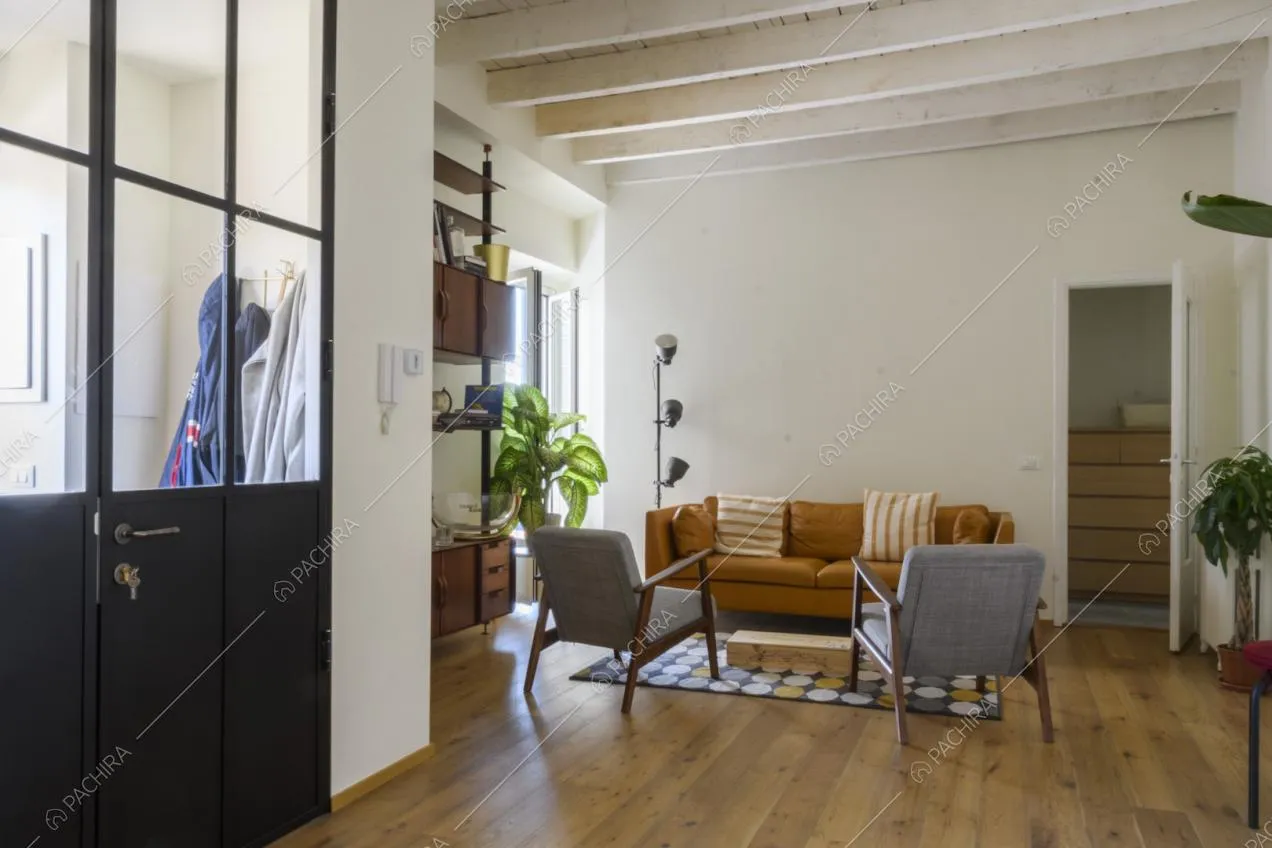 Divano e poltroncine sul pavimento in parquet e tappeto con fantasia geometrica