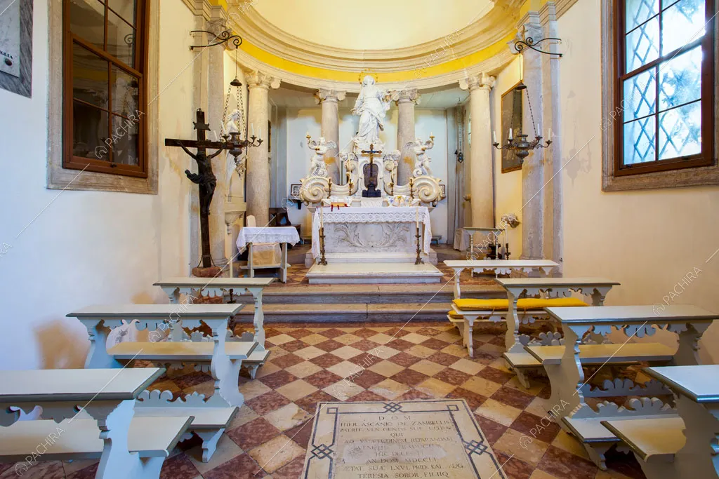 Cappella con pavimento a scacchi, statue e panche bianche