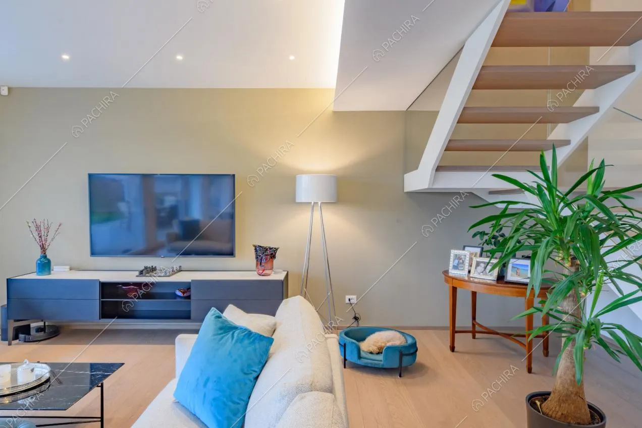Divano bianco nella sala con parete beige, pavimento in parquet e scale