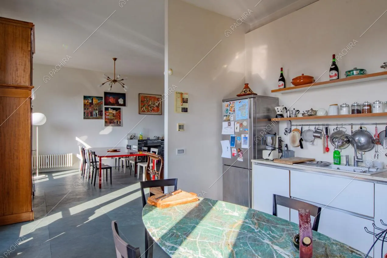Cucina a parete bianca e vista sul tavolo da pranzo rosso nella zona living